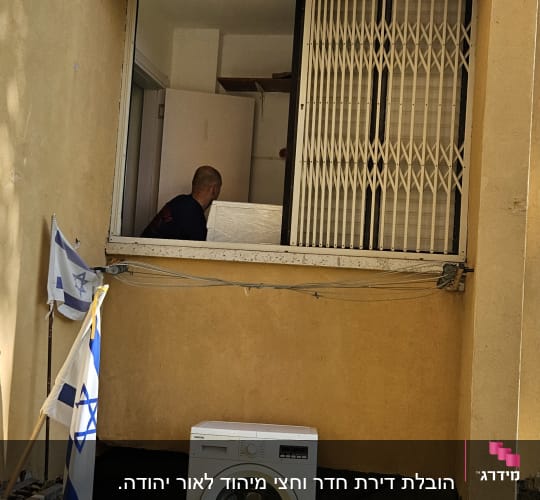 אדם מעביר מכשיר חשמלי דרך חלון פתוח